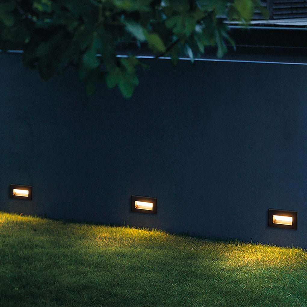 Three recessed step lights low on a garden wall lighting the lawn at night