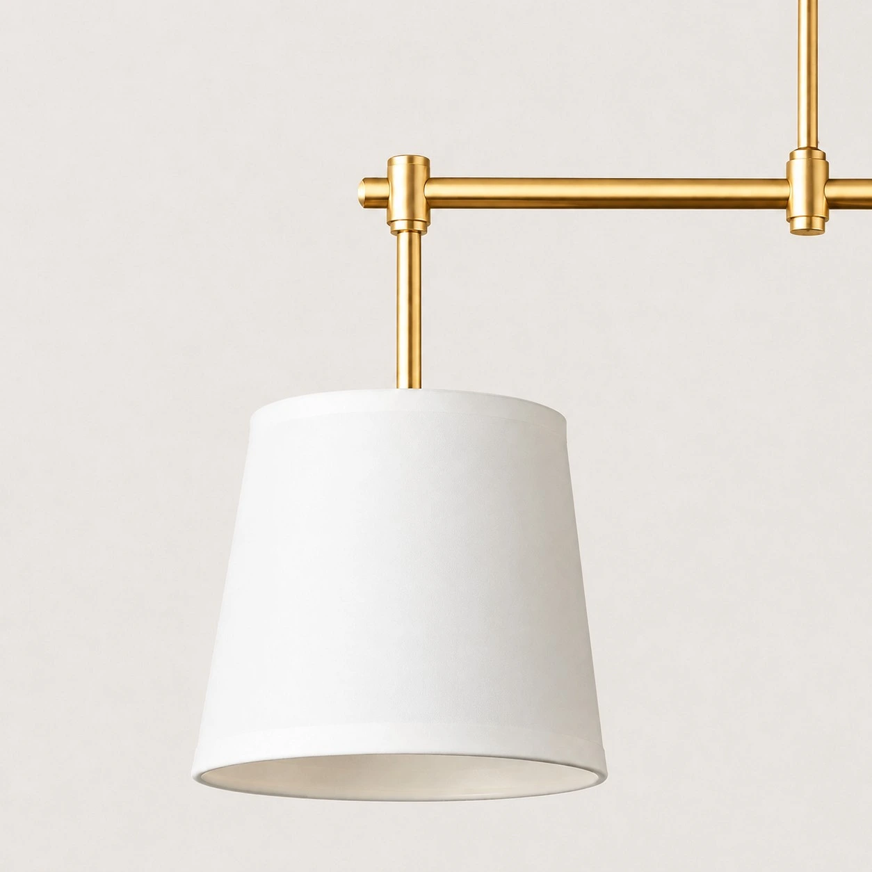 Close-up of Dumora white fabric drum shade on brushed brass arm
