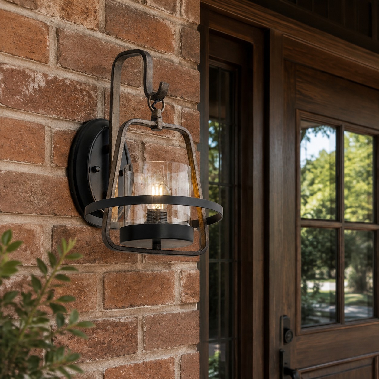 Rust finish clear glass wall sconce beside a brick entry