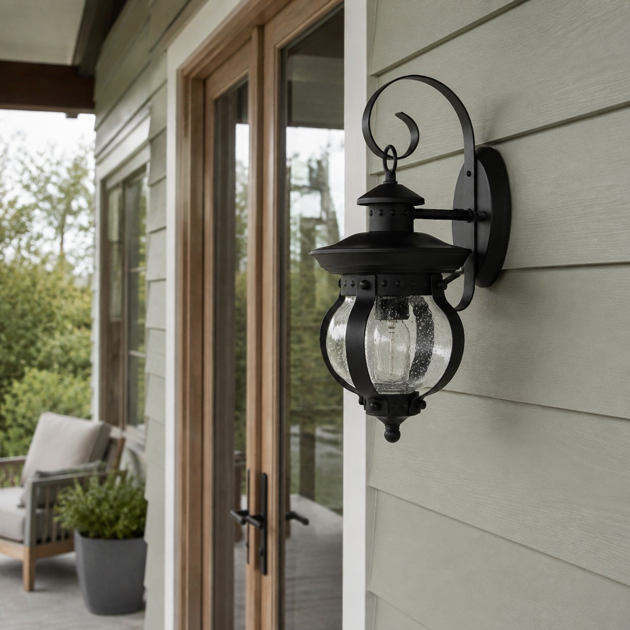 Black outdoor wall lantern lighting a garden-side patio wall