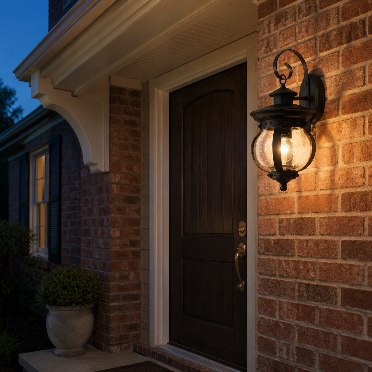 Black seeded glass wall lantern beside a covered brick porch