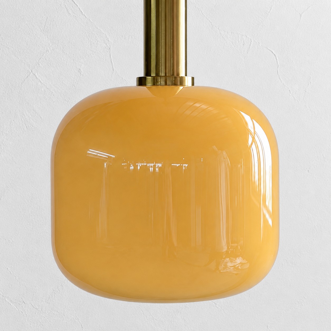 Close view of the rounded glossy yellow glass shade and brass holder