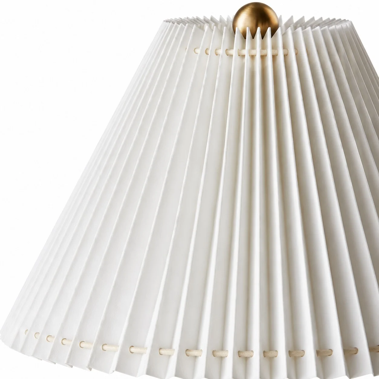 Close-up of white pleated fabric lampshade with gold finial